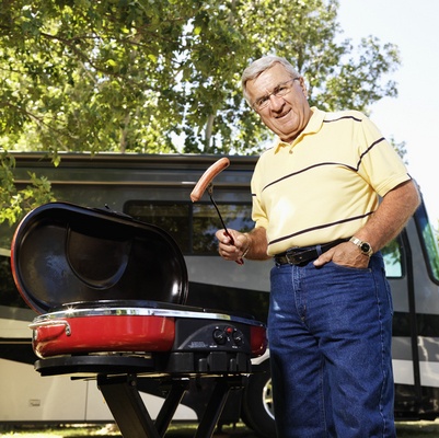 Man grilling hot dogs by SUV